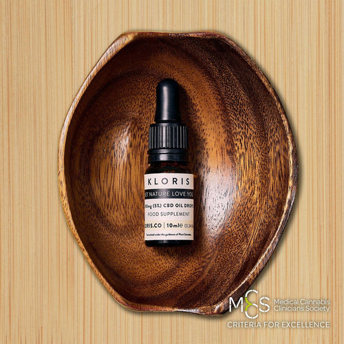 Kloris CBD oil dropper bottle in a wooden bowl on a wooden background