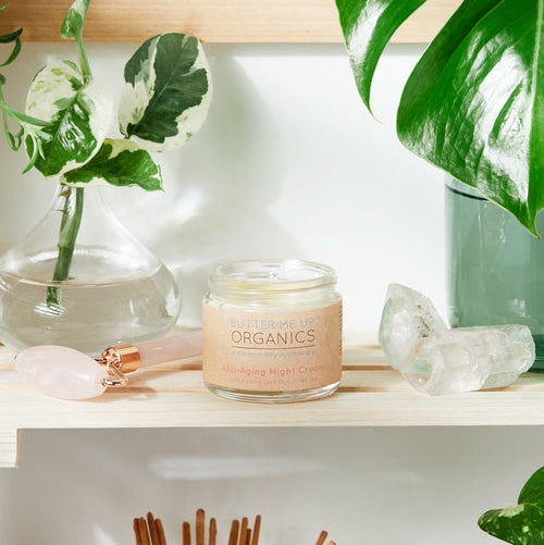 Candle labeled 'Organics' on a shelf with plants and crystals