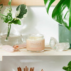 Candle labeled 'Organics' on a shelf with plants and crystals
