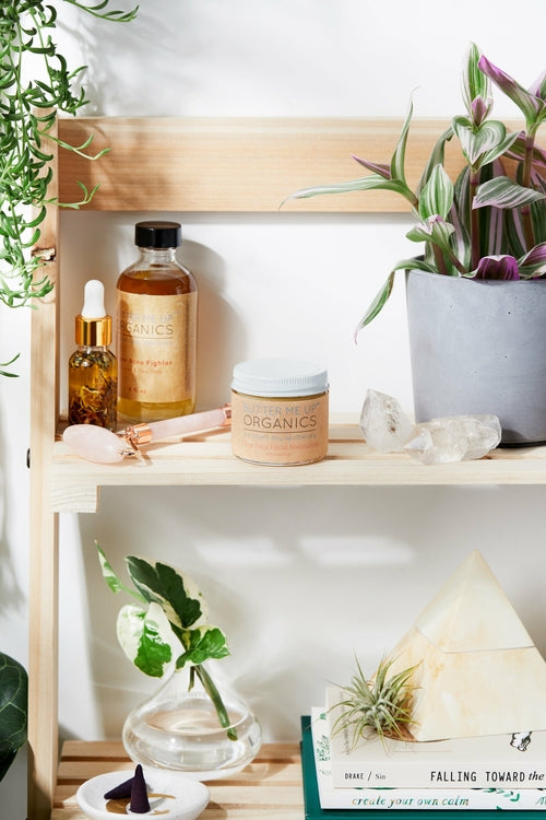 Shelf with skincare products and plants on a white wall