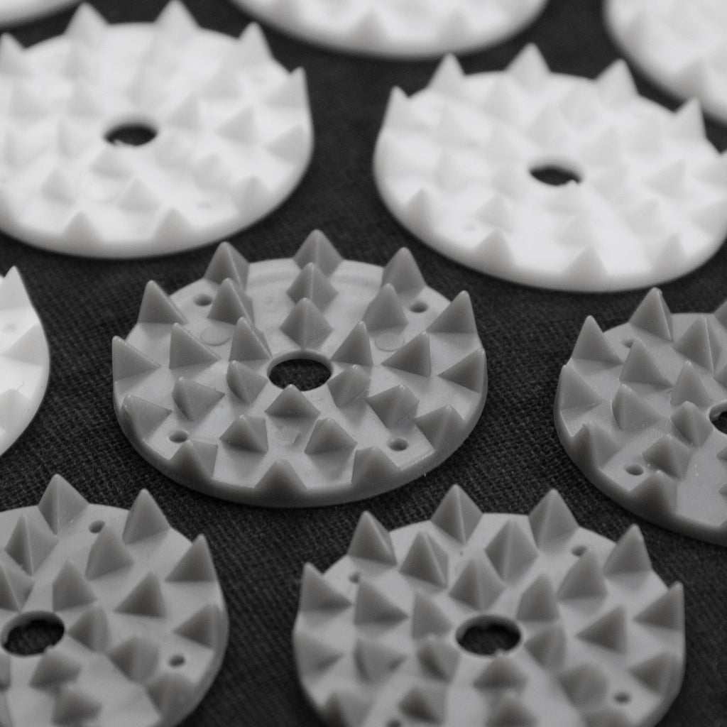White plastic components with spike-like patterns on a black background