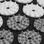 White plastic components with spike-like patterns on a black background