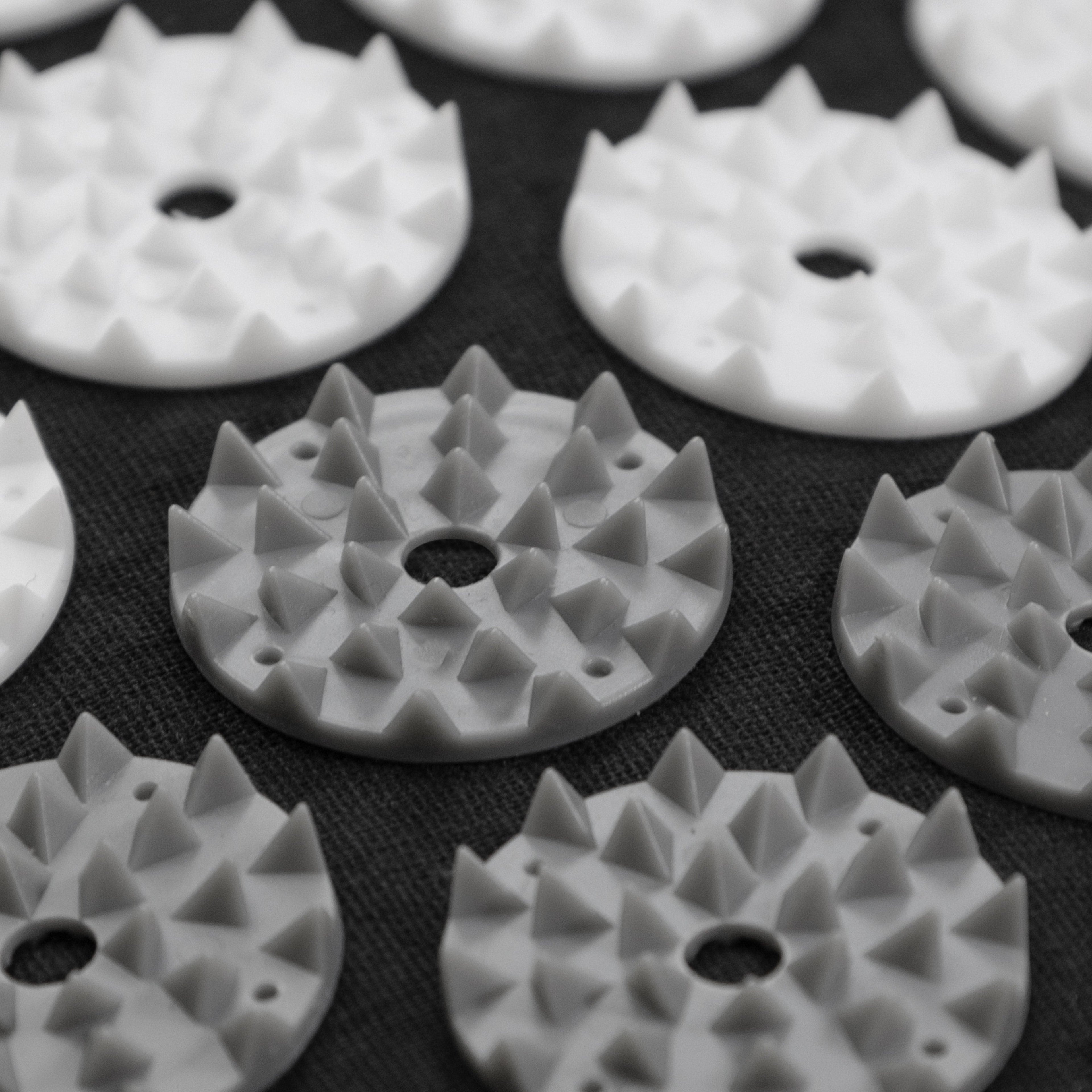 White plastic components with spike-like patterns on a black background