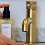 Gold faucet and Henley Woods product on a marble surface