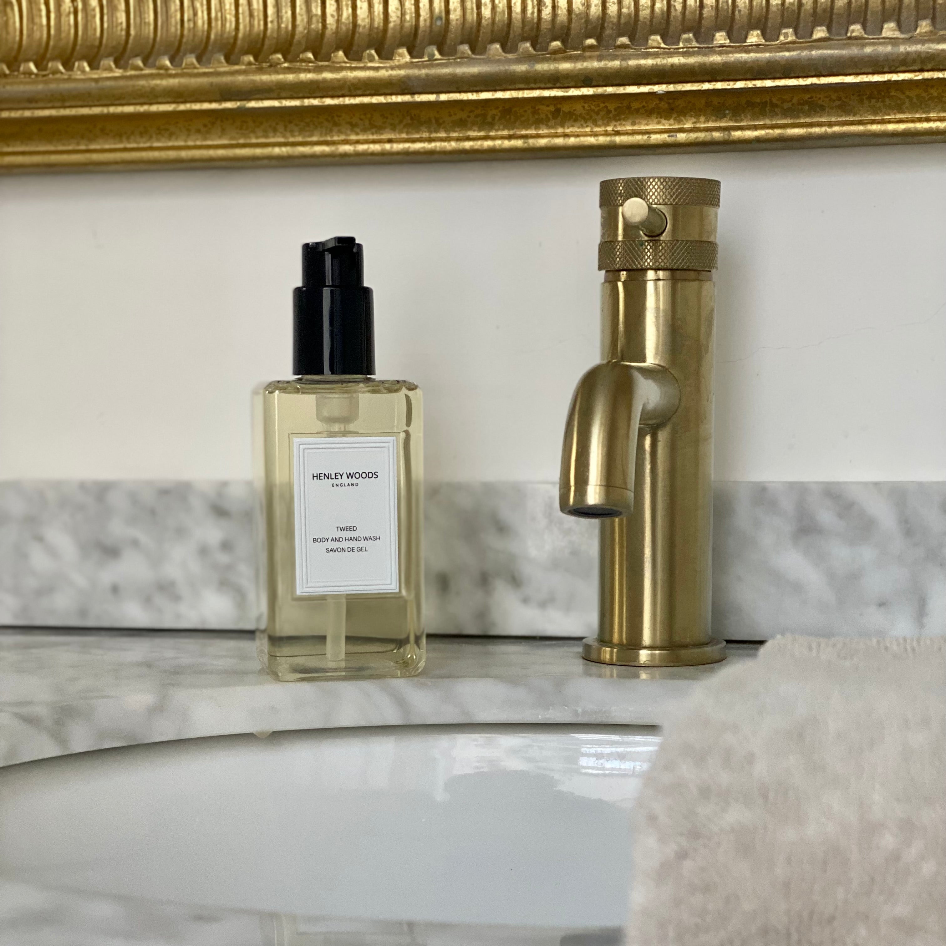 Bathroom setting with a bottle of Honey Muse perfume and a gold faucet.