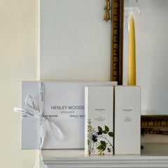 Henley Woods product packaging on a shelf with a candle and decorative mirror.