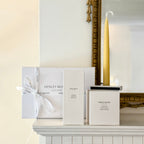 Henley Woods candles and packaging on a fireplace mantel with a decorative mirror in the background.
