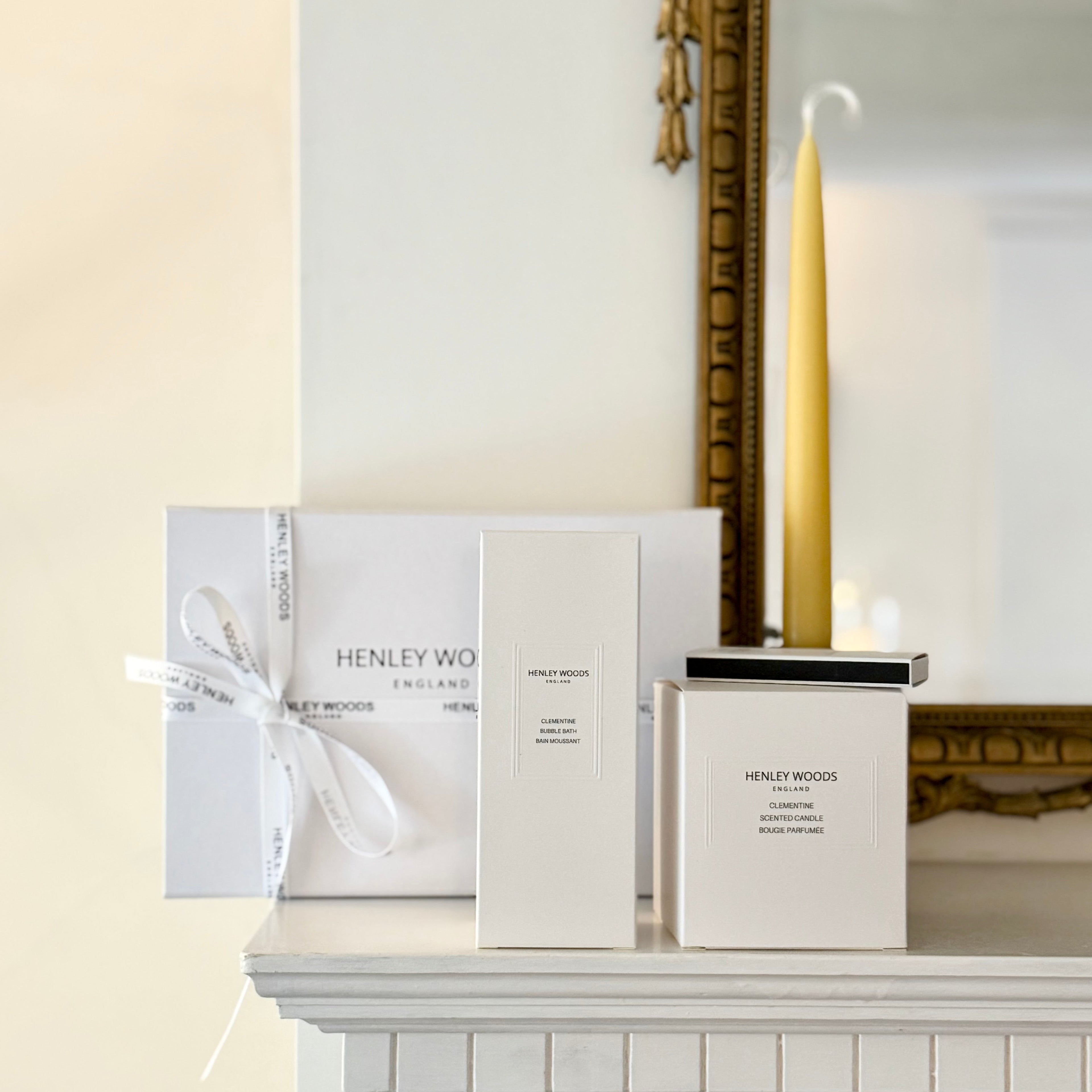 Henley Woods candles and packaging on a fireplace mantel with a decorative mirror in the background.