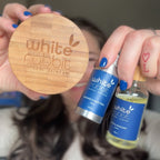 Person holding a wooden disc and two small bottles labeled 'White Rabbit' with hair in the background.