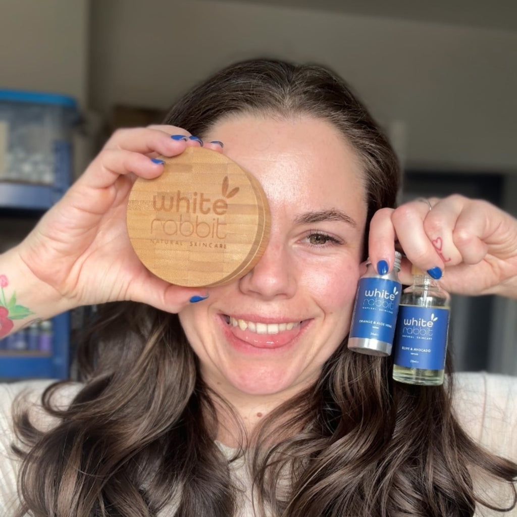 Woman holding a wooden disc and two blue bottles with 'White Mulberry' branding.
