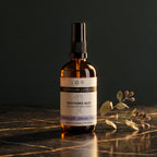 Bottle of KLORIS Soothing Mist on a dark surface with leaves.
