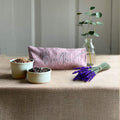 Decorative items on a table including a pink pouch, small plants, and lavender.