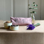 Decorative items on a table including a pink pouch, small plants, and lavender.