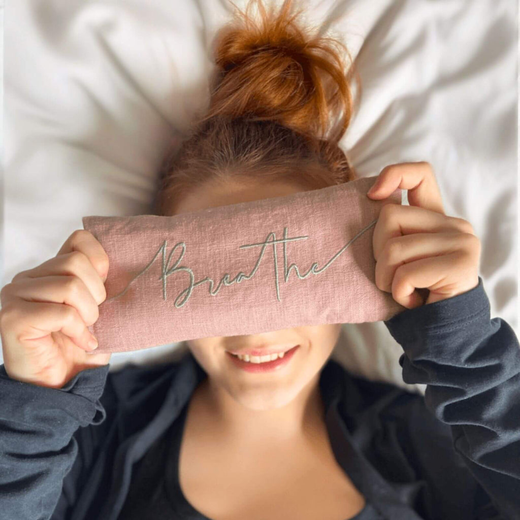 Person holding a pink band with 'Breathe' text over their eyes