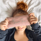 Person holding a pink band with 'Breathe' text over their eyes