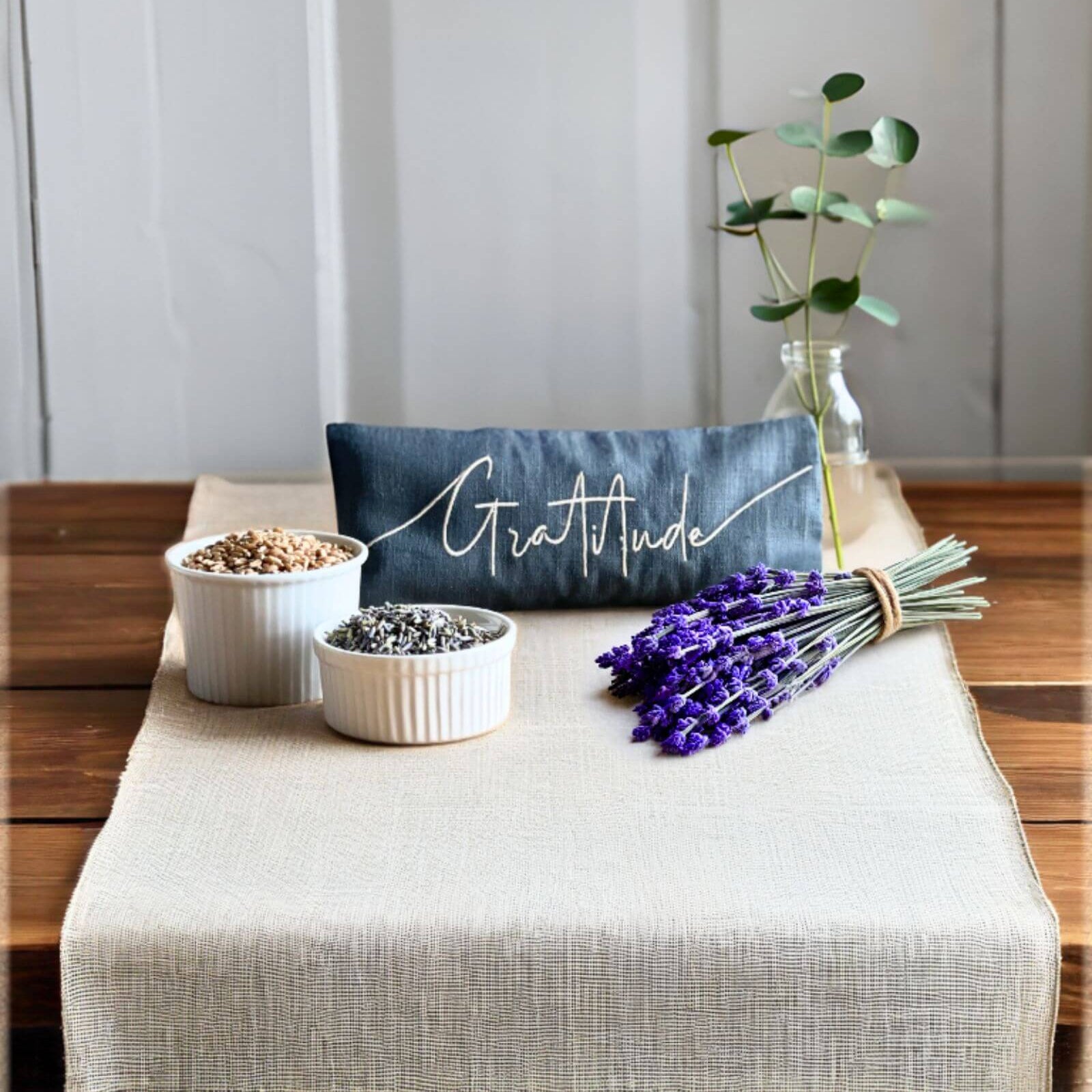 Decorative setting with 'Gratitude' pillow, plants, and lavender on a wooden surface.