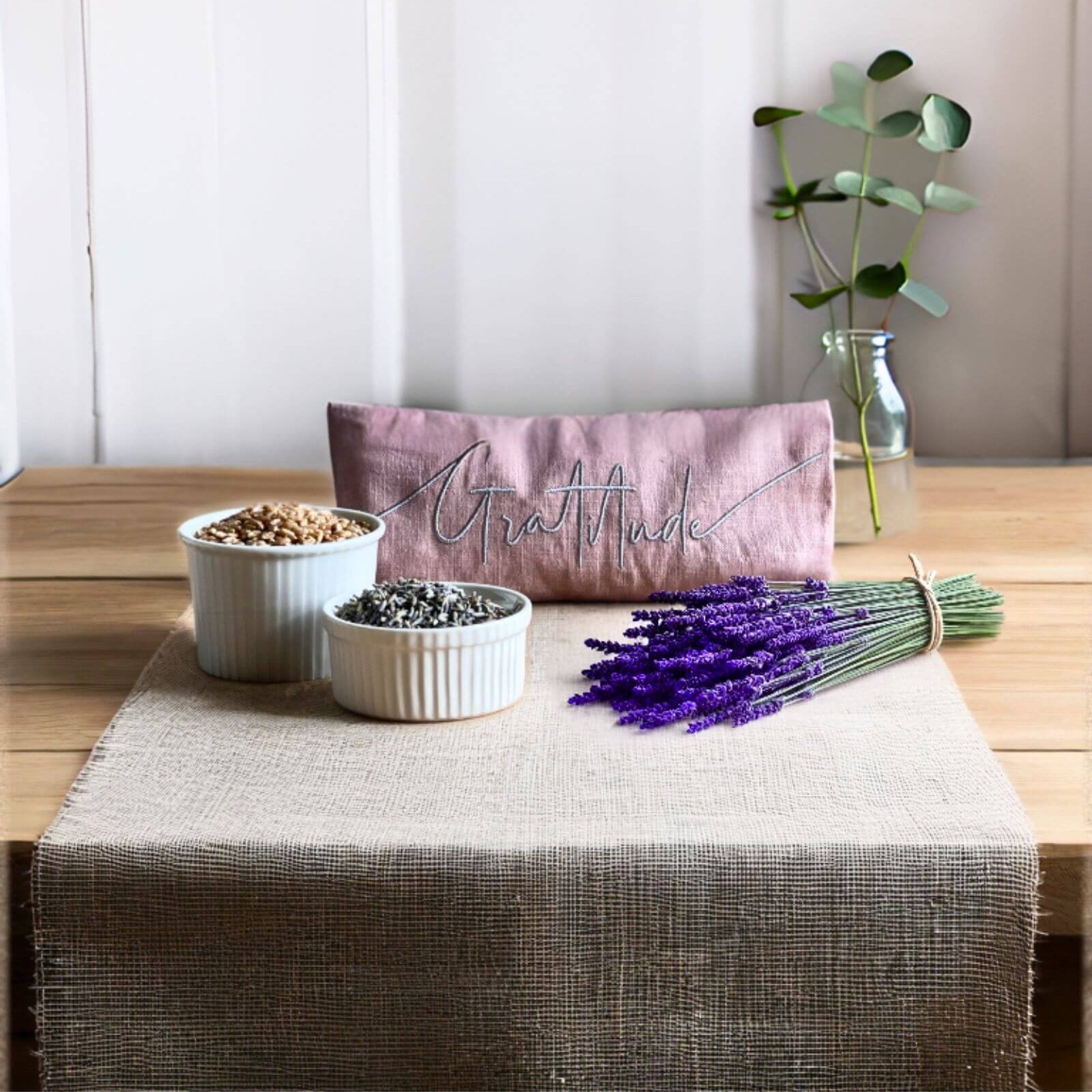 Table setting with lavender, small bowls, and a pink pillow with 'Gratitude' on a wooden table.
