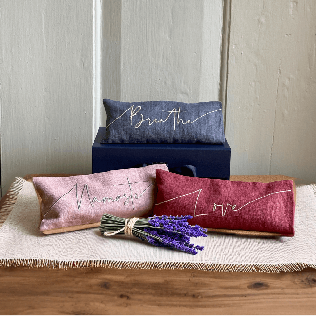 Three decorative pillows with text on a wooden surface with lavender flowers.