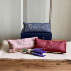 Three decorative pillows with text on a wooden surface with lavender flowers.