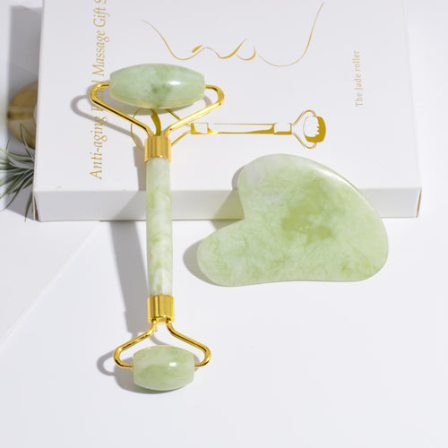 Green jade facial roller and gua sha tool on a white background