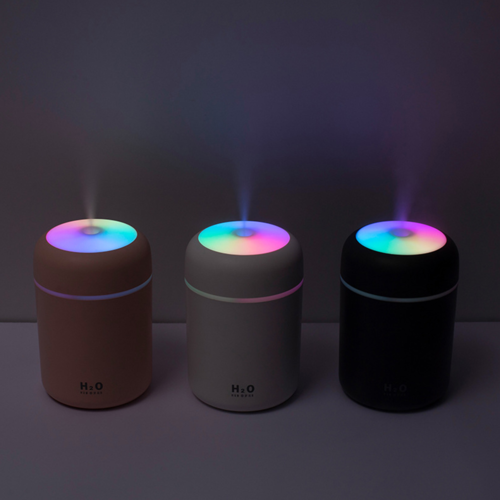 Three colorful humidifiers with LED lights on a dark background
