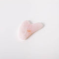 Heart-shaped pink object with a small yellow detail on a light gray background
