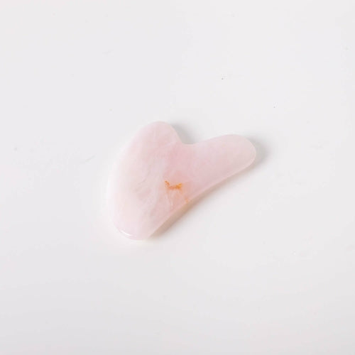 Heart-shaped pink object with a small yellow detail on a light gray background