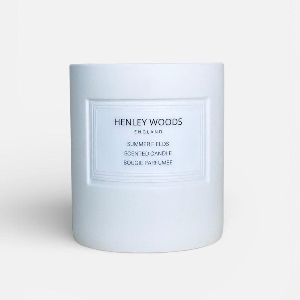 White candle with 'Henley Woods' branding on a light gray background
