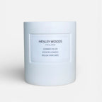 White candle with 'Henley Woods' branding on a light gray background