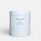 White candle with 'Henley Woods' branding on a light beige background