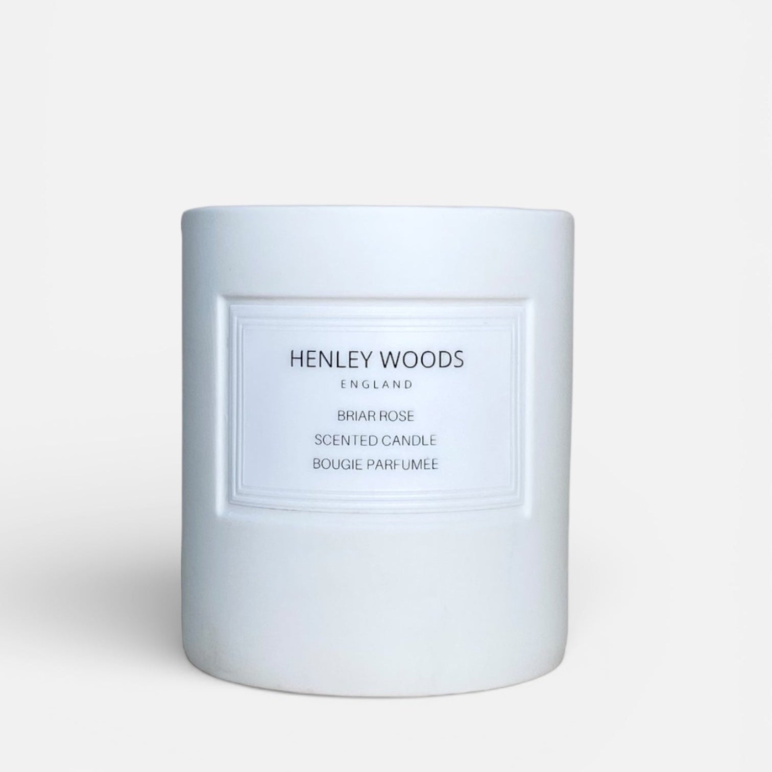 White candle with 'Henley Woods' branding on a light beige background