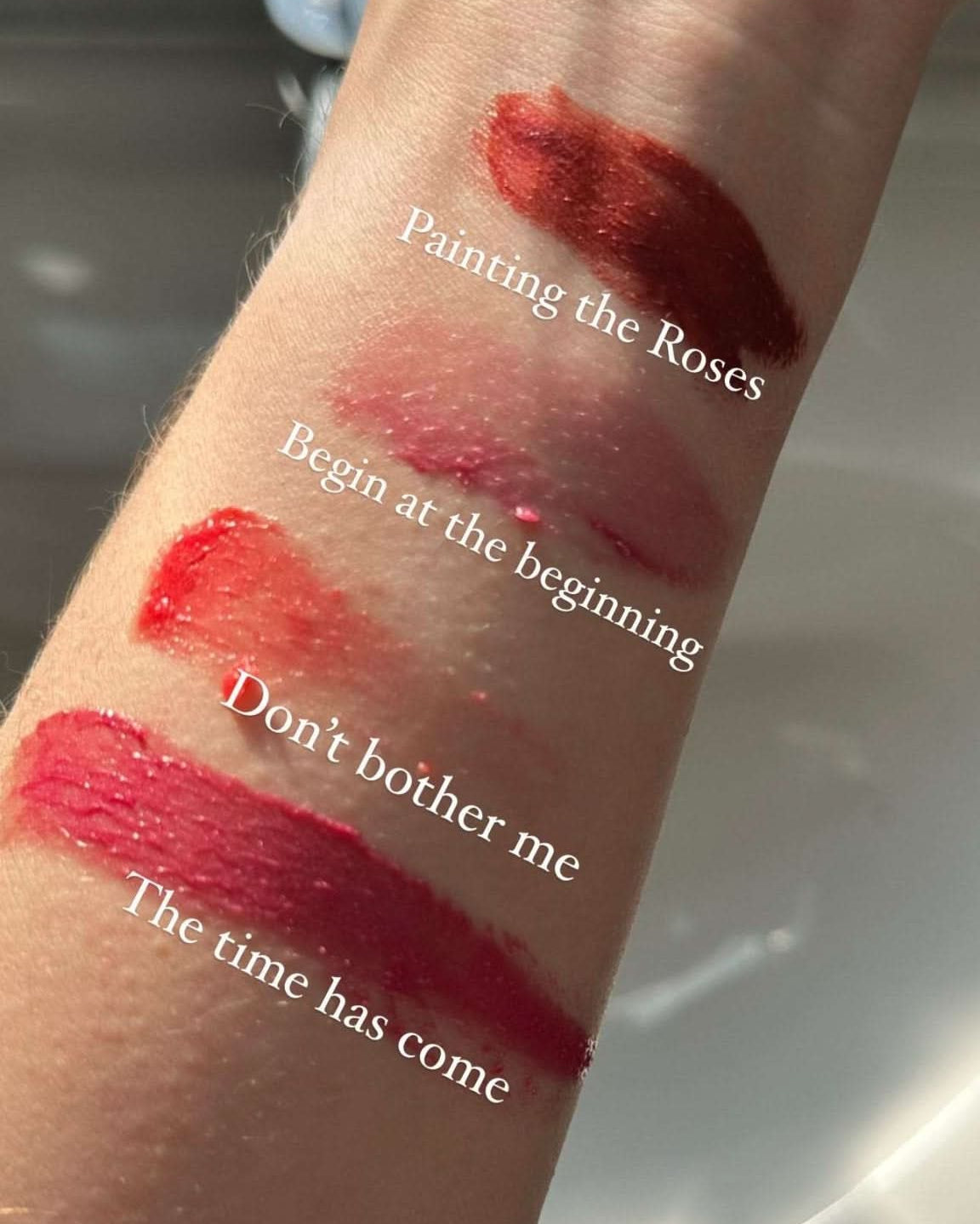 Lipstick swatches on a wrist with text labels